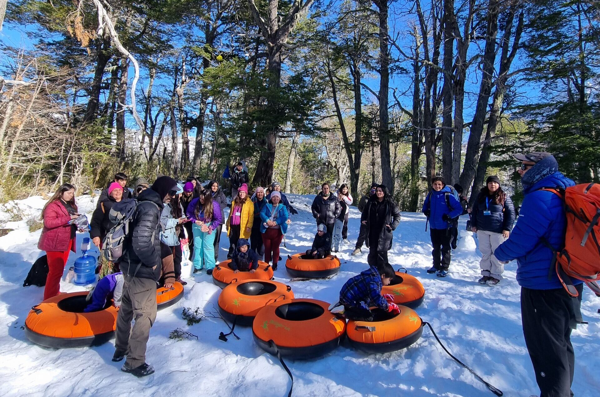 a group of people standing in snow with tubes